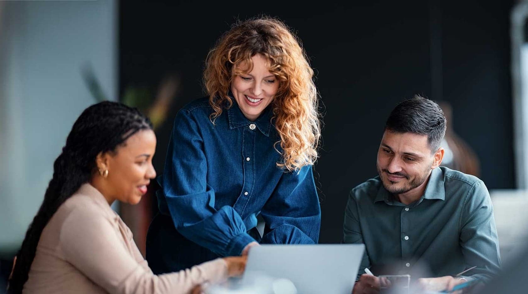 Three education professionals working together at a laptop